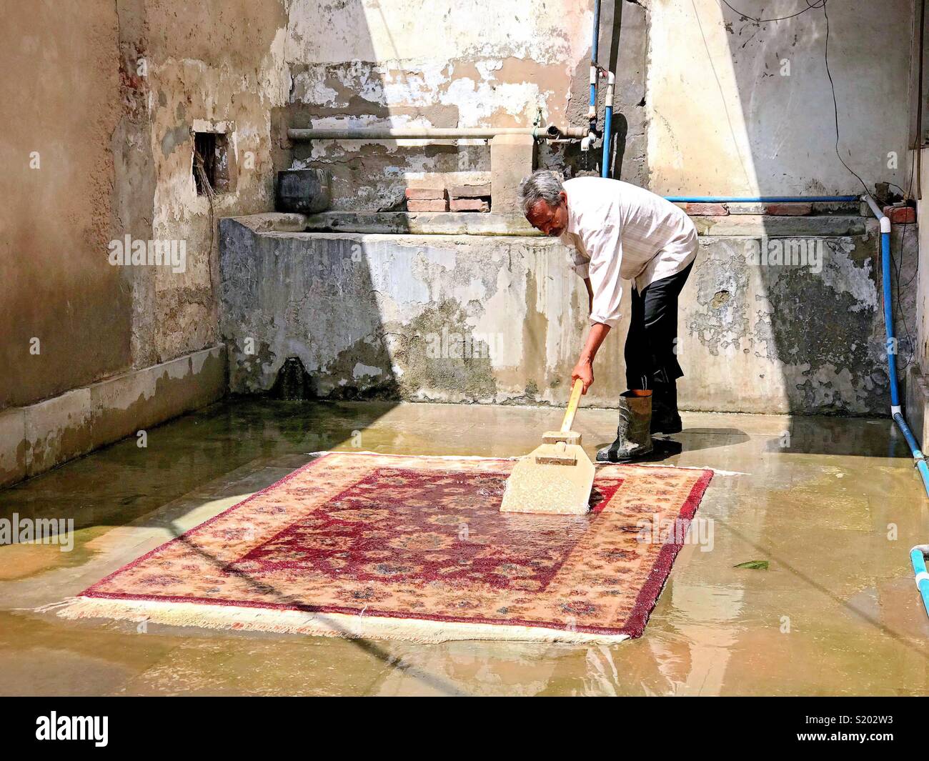 Un homme se lave un tapis à un magasin d'artisanat à Agra, en Inde. Banque D'Images