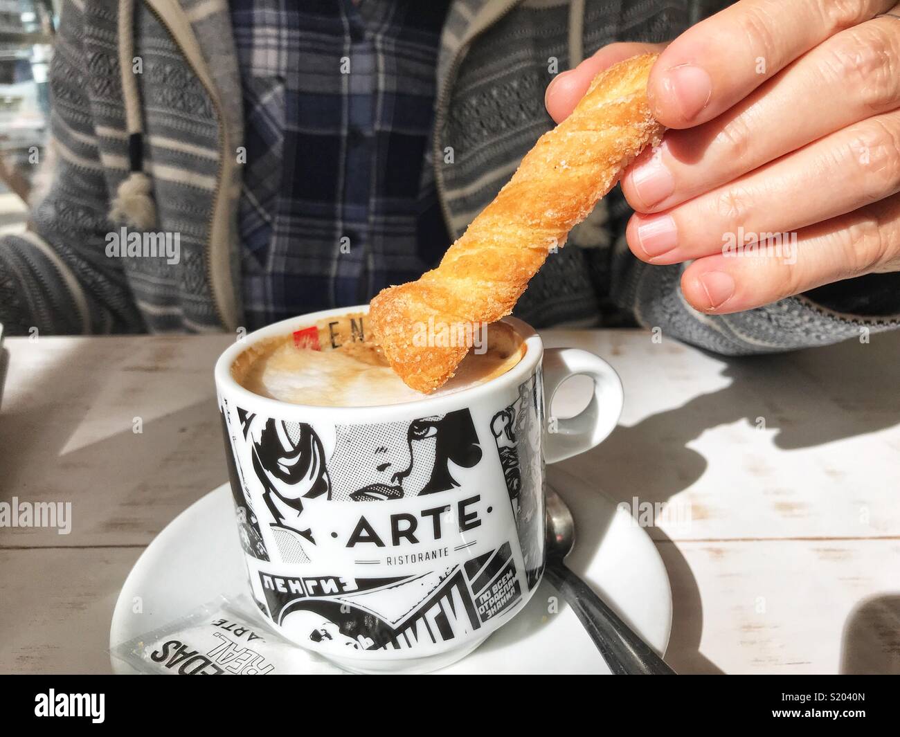 Femme un biscuit tremper dans une tasse de cappuccino dans un café, midsection view Banque D'Images
