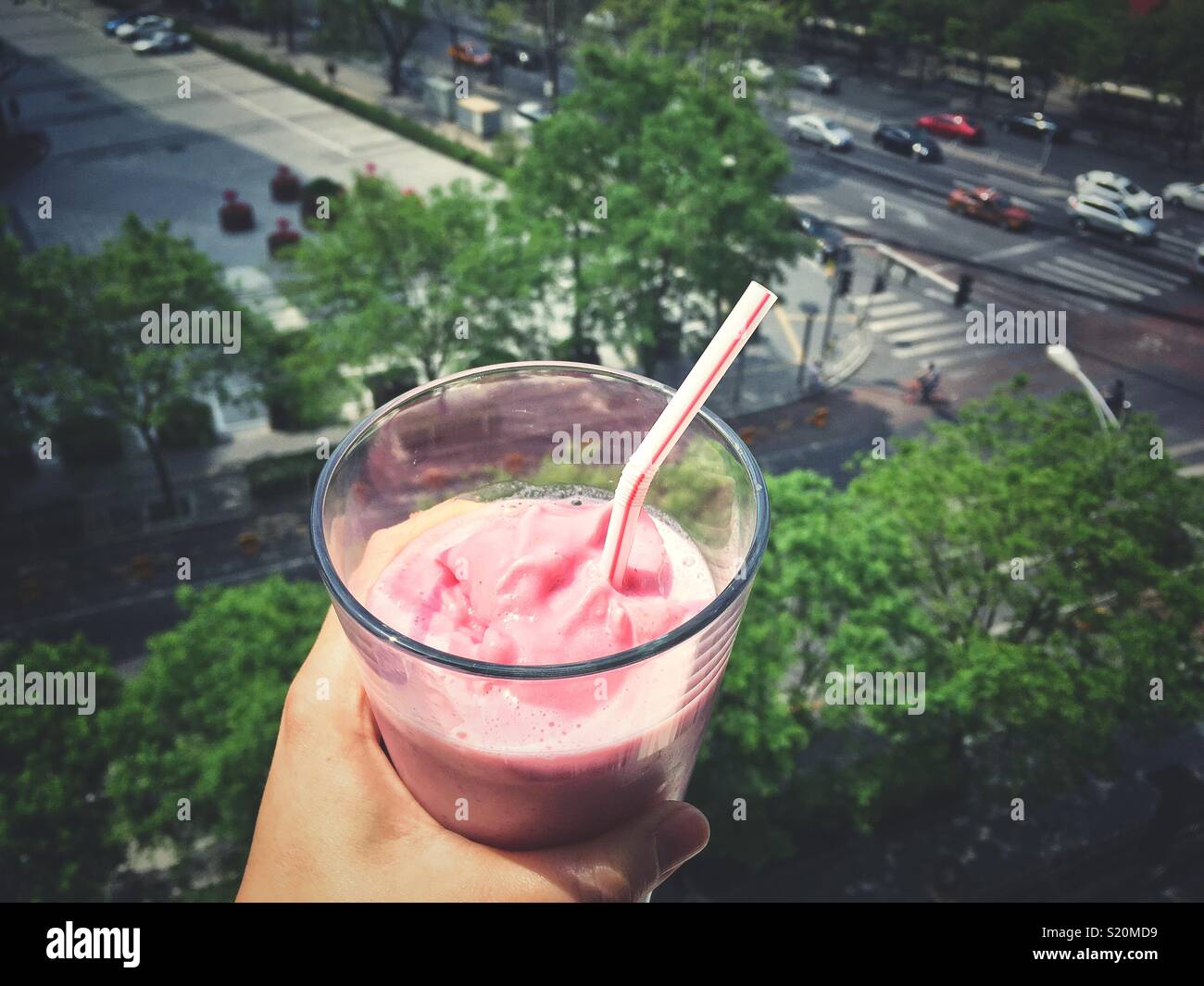 Avoir un verre de lait fouetté aux fraises à un balcon. Banque D'Images