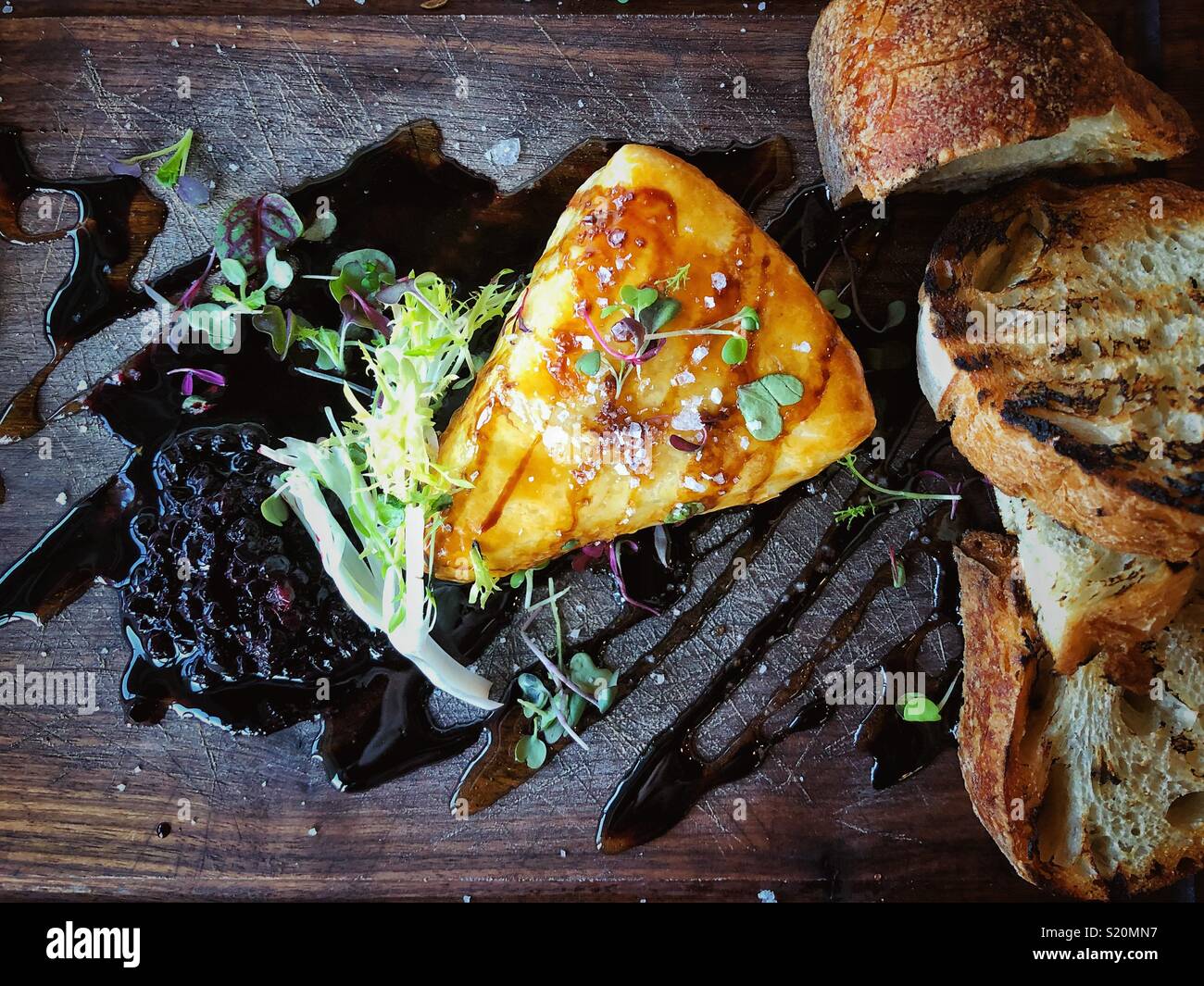 Brie au four sur une cale en bois servant de sélection avec du pain grillé et sa compote de bleuets sauvages Banque D'Images Brie au four sur une cale en bois servant de sélection avec du pain grillé et sa compote de bleuets sauvages Banque D'Images