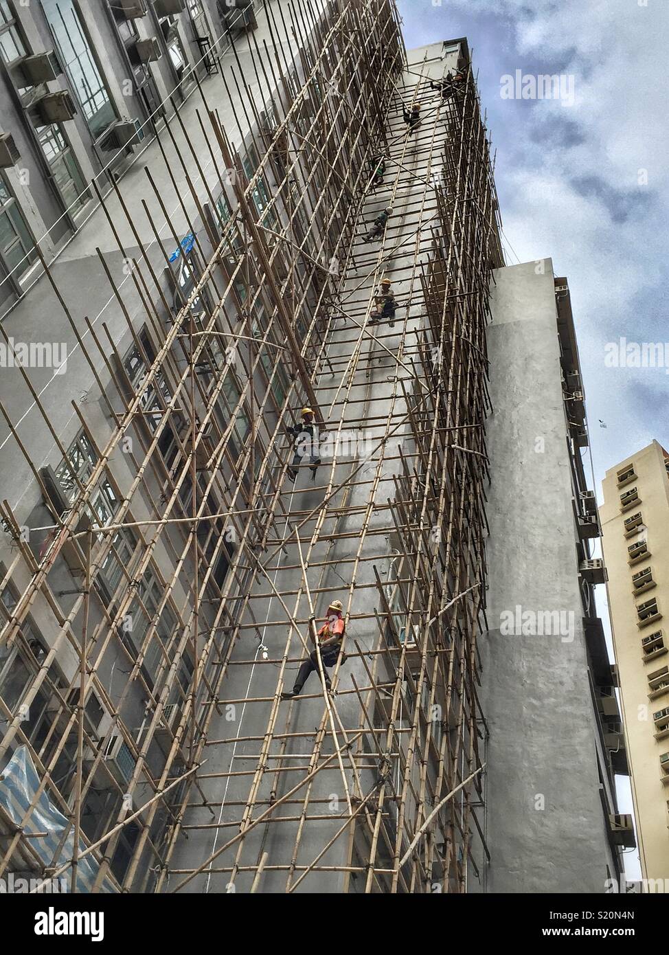Ouvriers forment une chaîne humaine pour démanteler les échafaudages en bambou après rénovation sur un immeuble d'habitation à Wan Chai, Hong Kong Island Banque D'Images