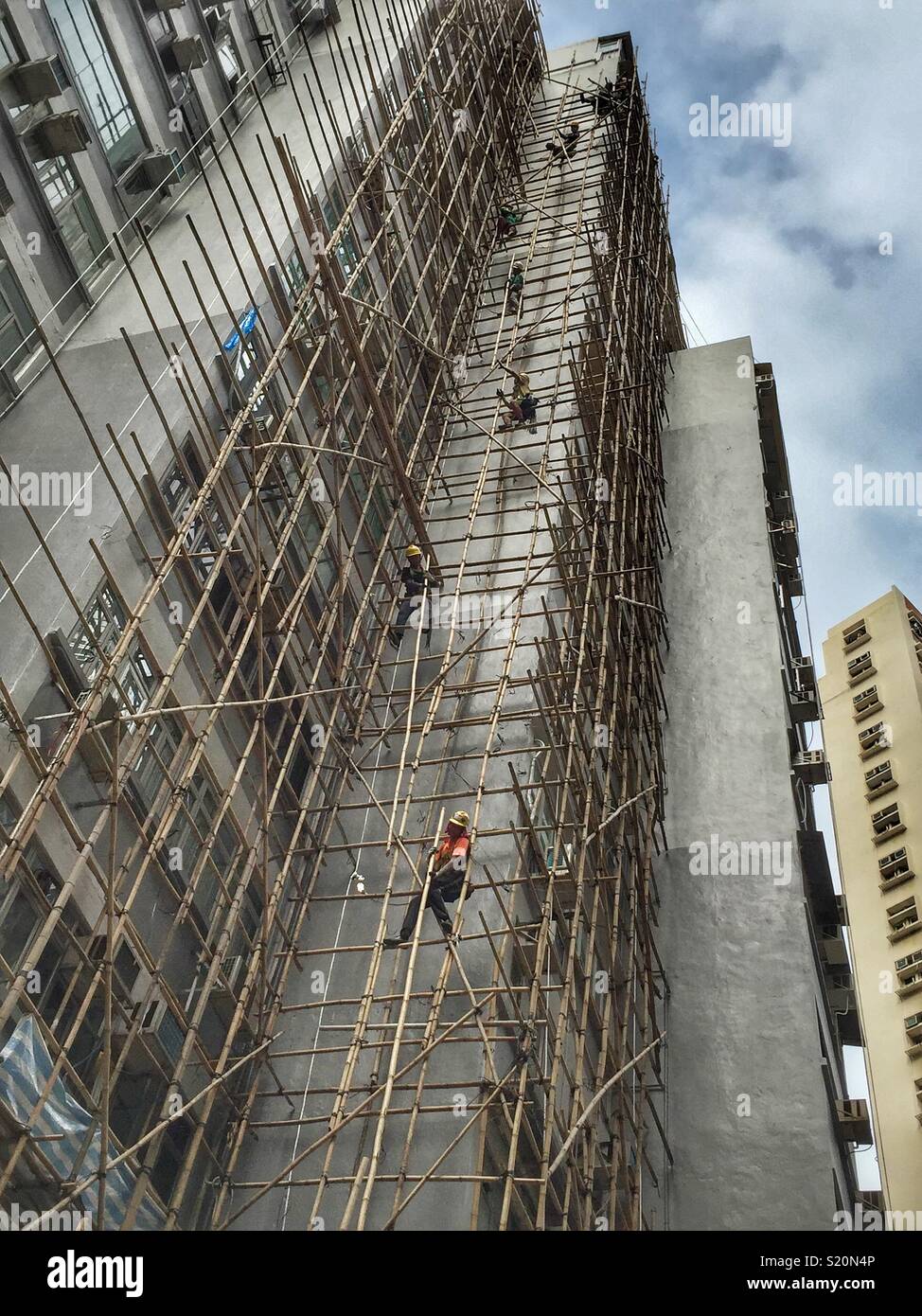 Ouvriers forment une chaîne humaine pour démanteler les échafaudages en bambou après rénovation sur un immeuble d'habitation à Wan Chai, Hong Kong Island Banque D'Images