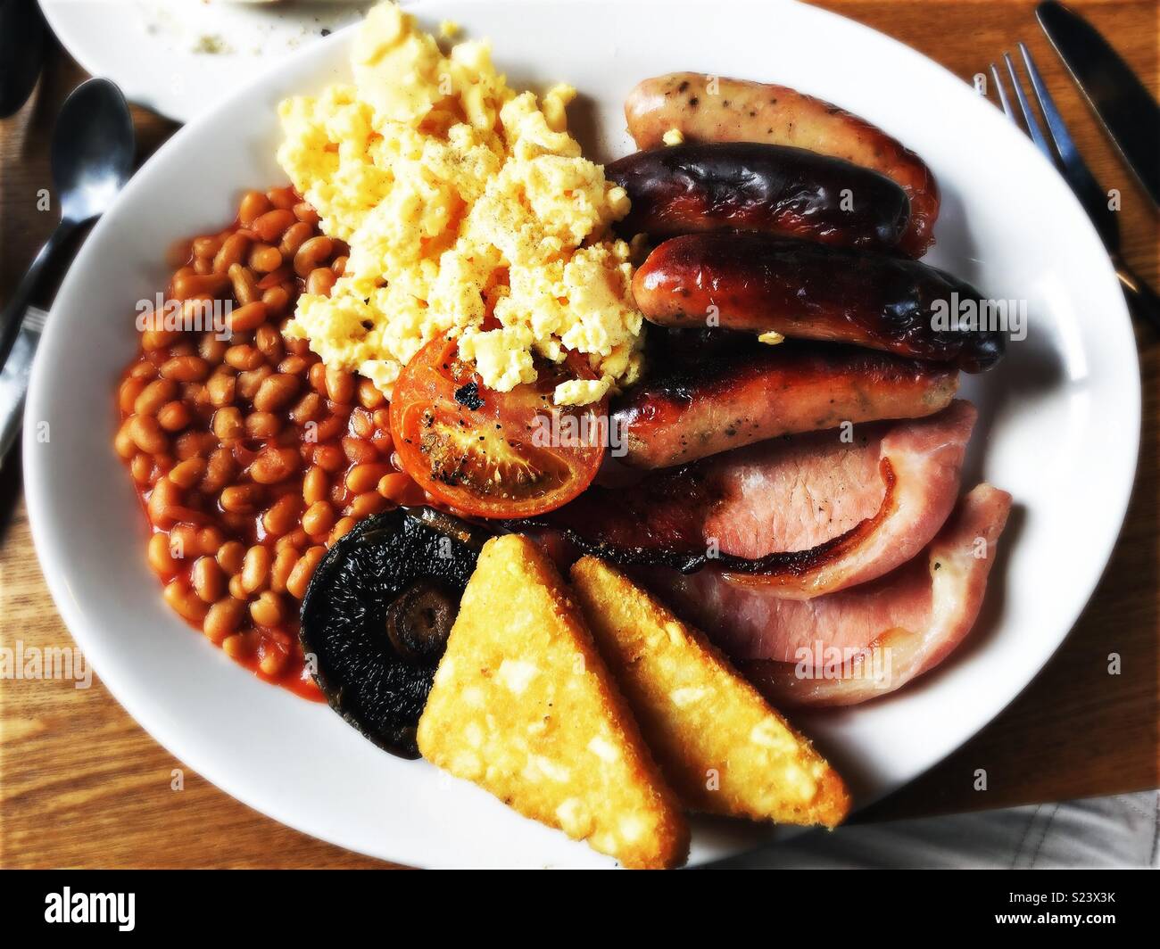 Le petit déjeuner anglais complet avec des saucisses, œufs, bacon, haricots, pommes de terre rissolées, champignons et tomates. Banque D'Images