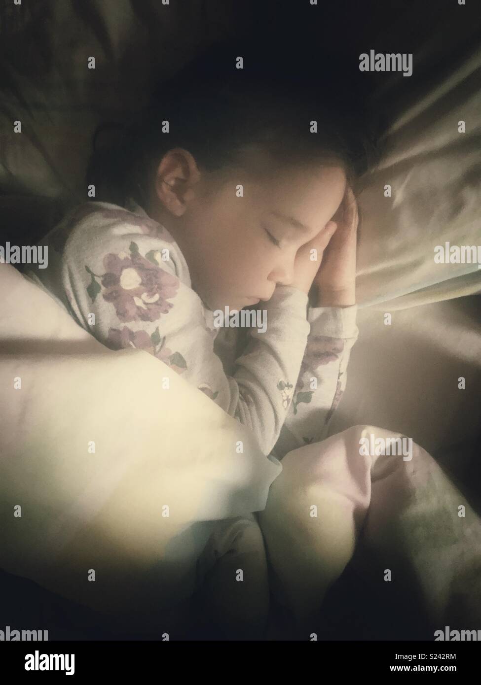 Une véritable image de 5 ans dormant dans le lit avec la lumière du matin sur visage Banque D'Images