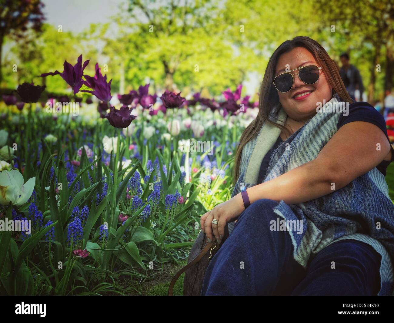 Une dame pose pour une photo assis dans un jardin. Banque D'Images