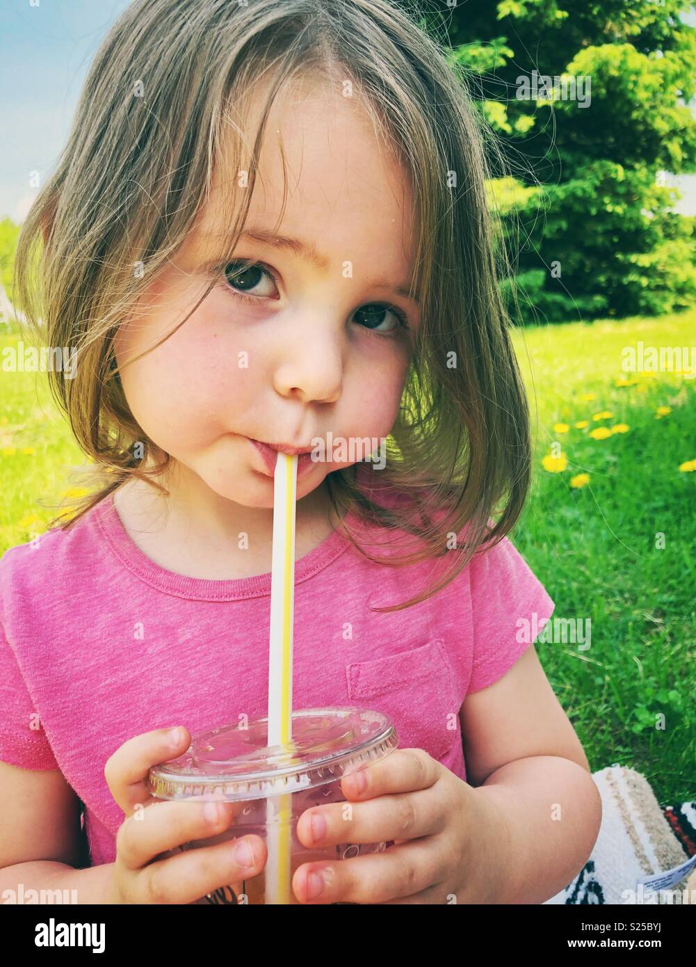 2 ans bébé fille boire du jus à partir de la tasse en plastique avec paille  en plastique Photo Stock - Alamy