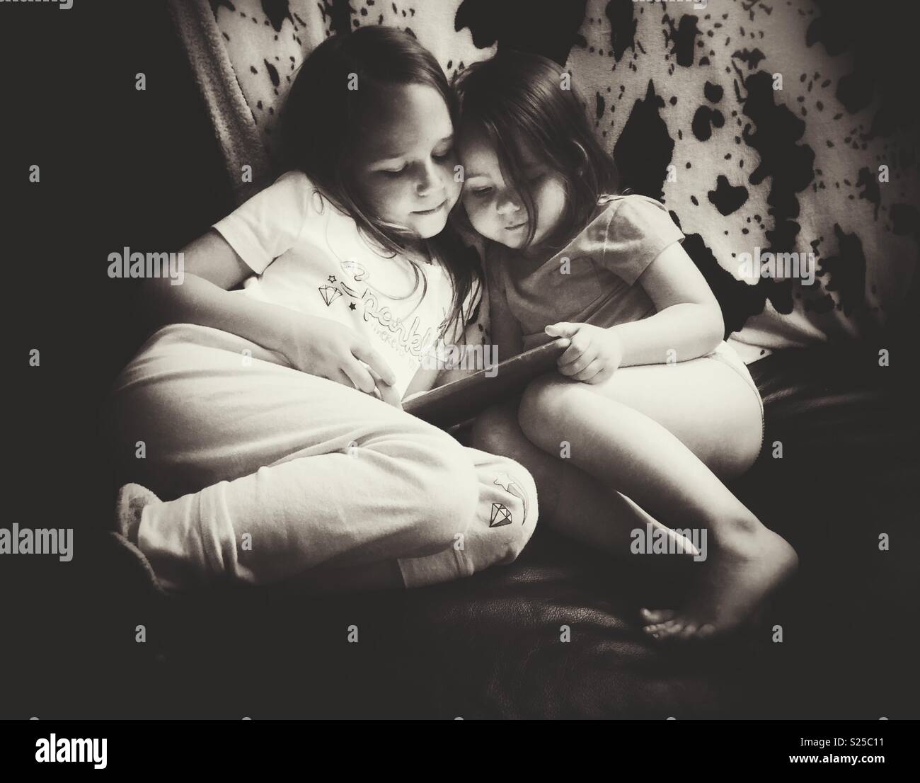Image en noir et blanc de deux soeurs assis ensemble à la recherche d'un comprimé Banque D'Images
