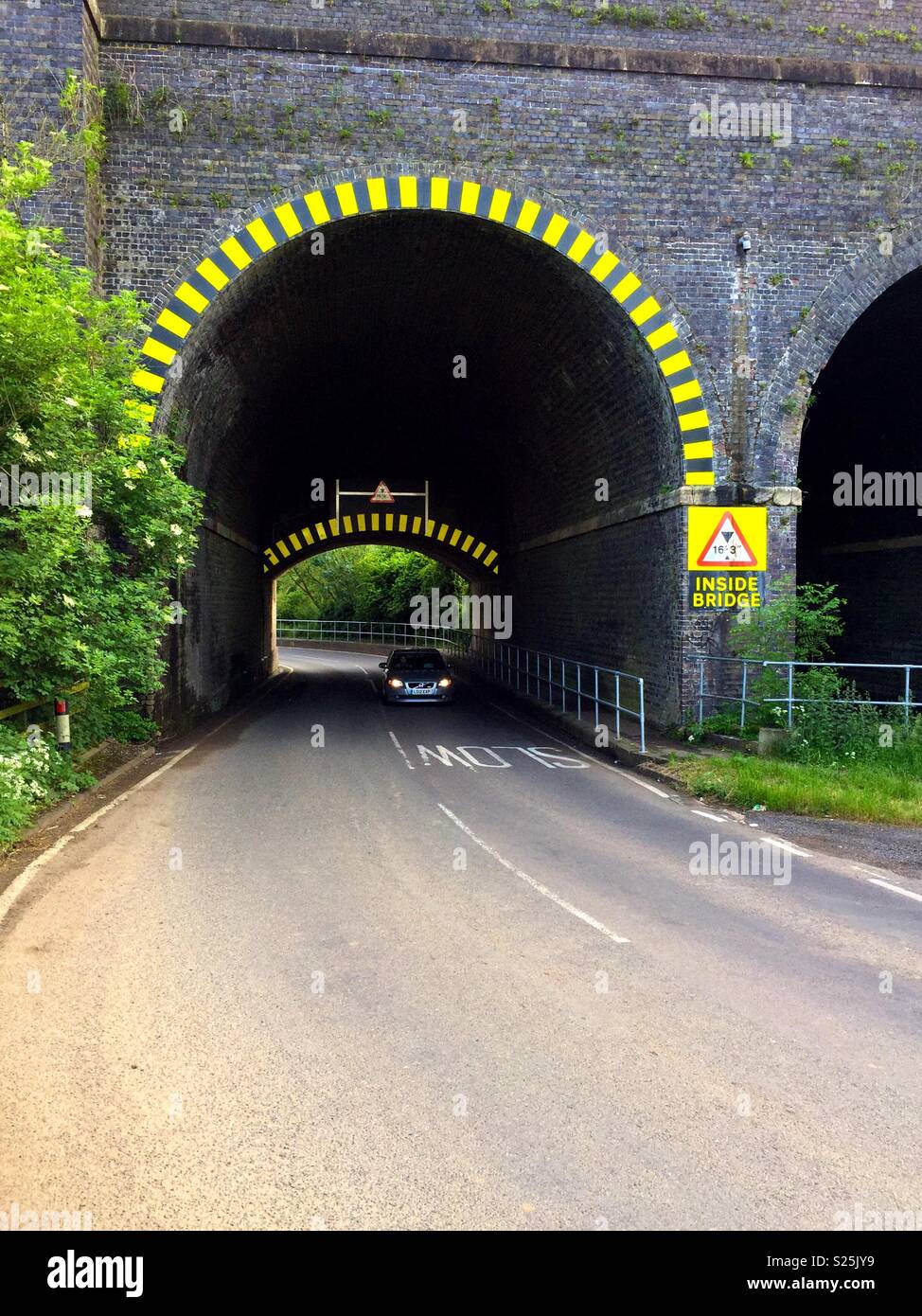 Pont du chemin de fer en bas avec avertissement de chevrons avec voiture intermédiaire Banque D'Images