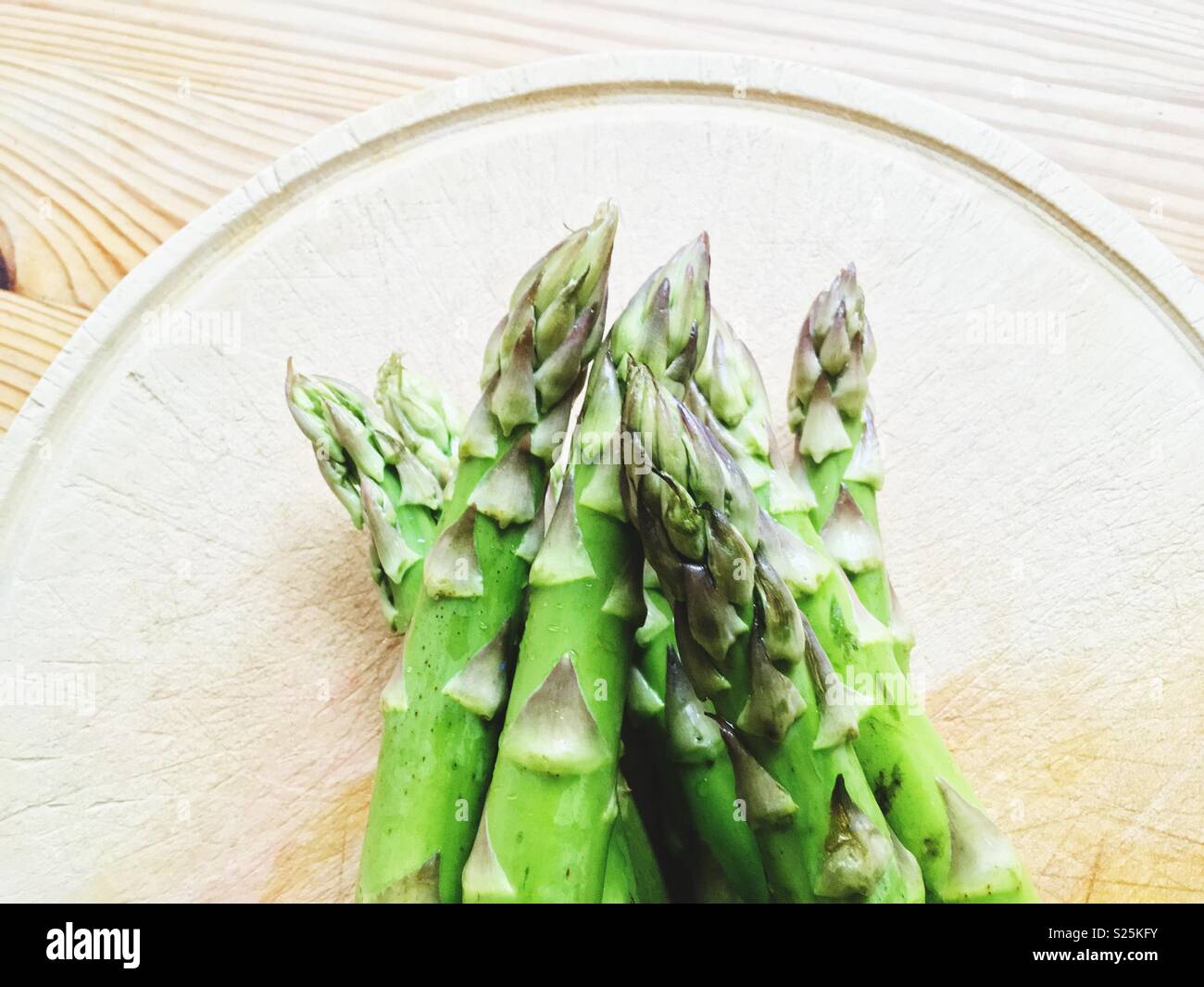 Asperges vertes sur une plaque de bois sur une table en bois Banque D'Images