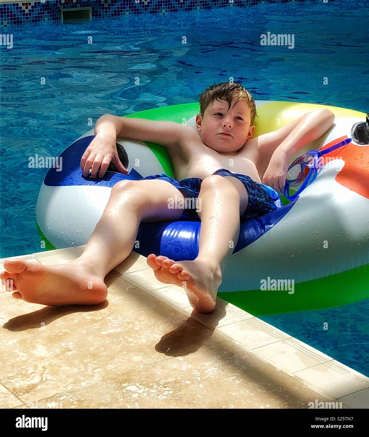 Garçon assis dans un anneau gonflable, le refroidissement de la piscine. Banque D'Images