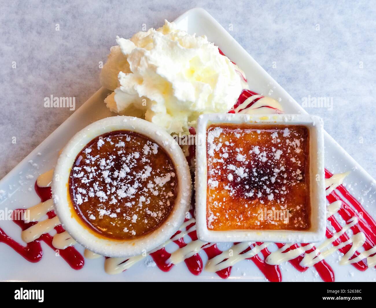 Crème brûlée dessert de deux façons, avec coulis de framboise, blanc d'un filet de chocolat et crème fouettée Banque D'Images