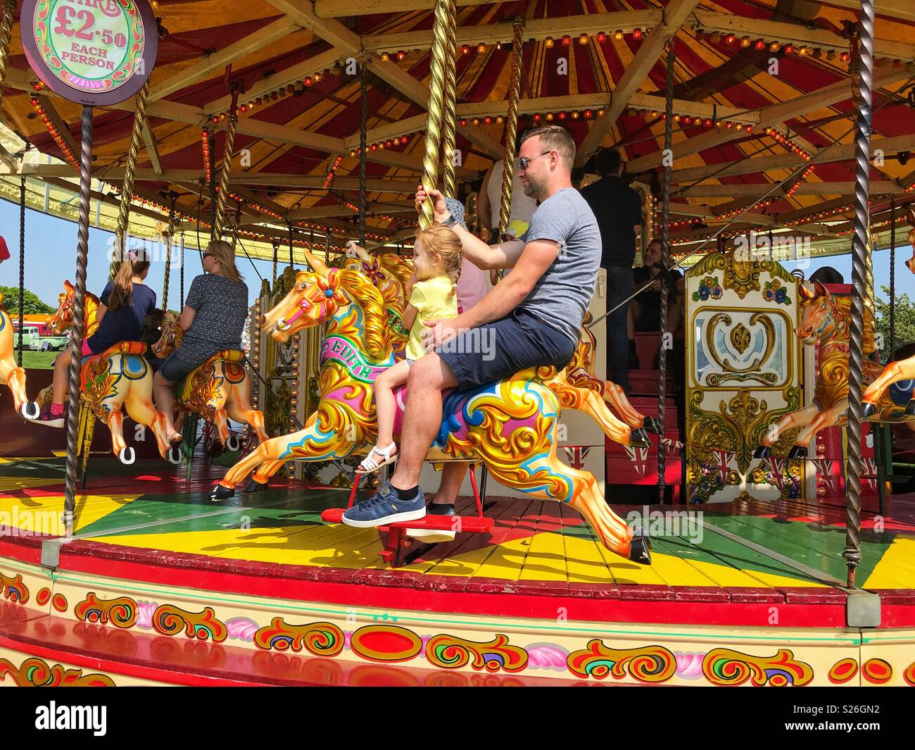 Père et fille à cheval sur un manège à un pays de foire. - Image de stock capturée avec un smartphone