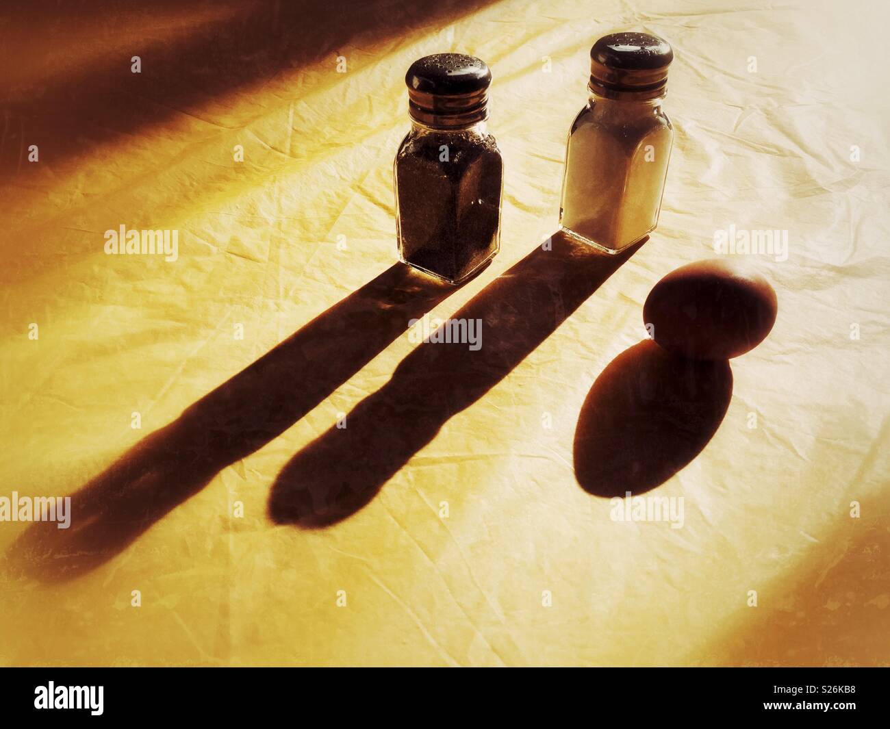 Sel, poivre et l'oeuf sur table ensoleillée avec de longues ombres Banque D'Images