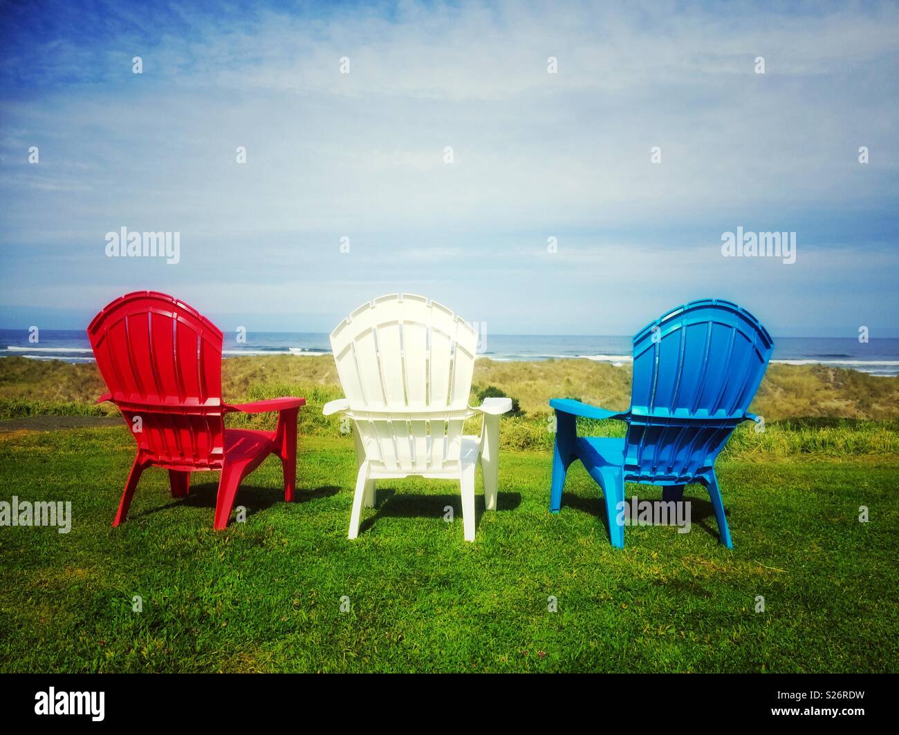 Trois couleurs rouge, blanc et bleu des chaises sur la pelouse vers l'océan pacifique, Oregon, USA. Banque D'Images