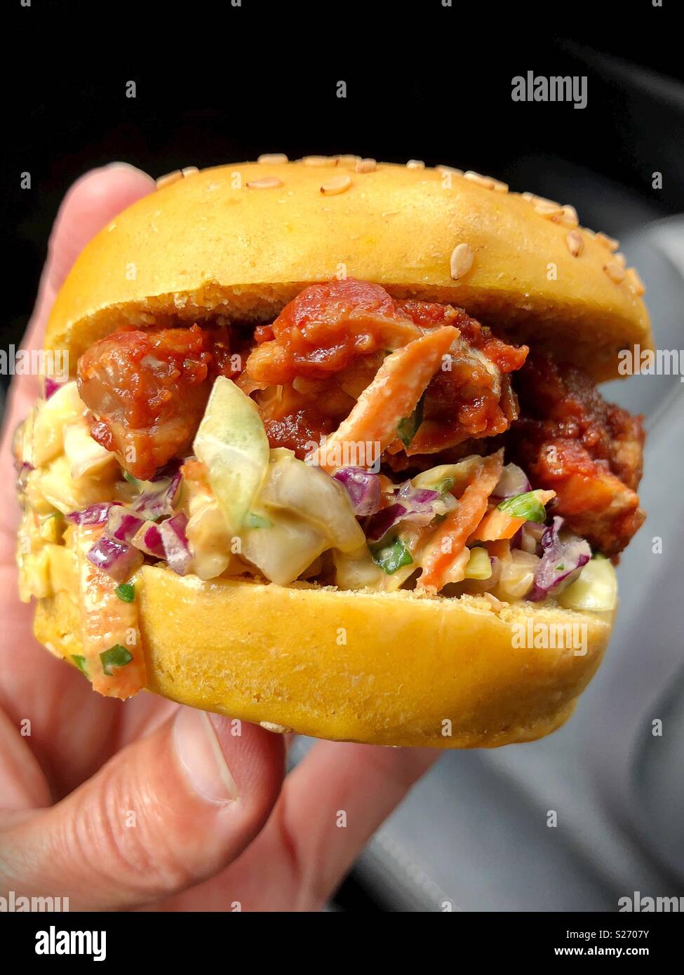 Une personne titulaire d'un végétalien tempeh bbq slider. Banque D'Images