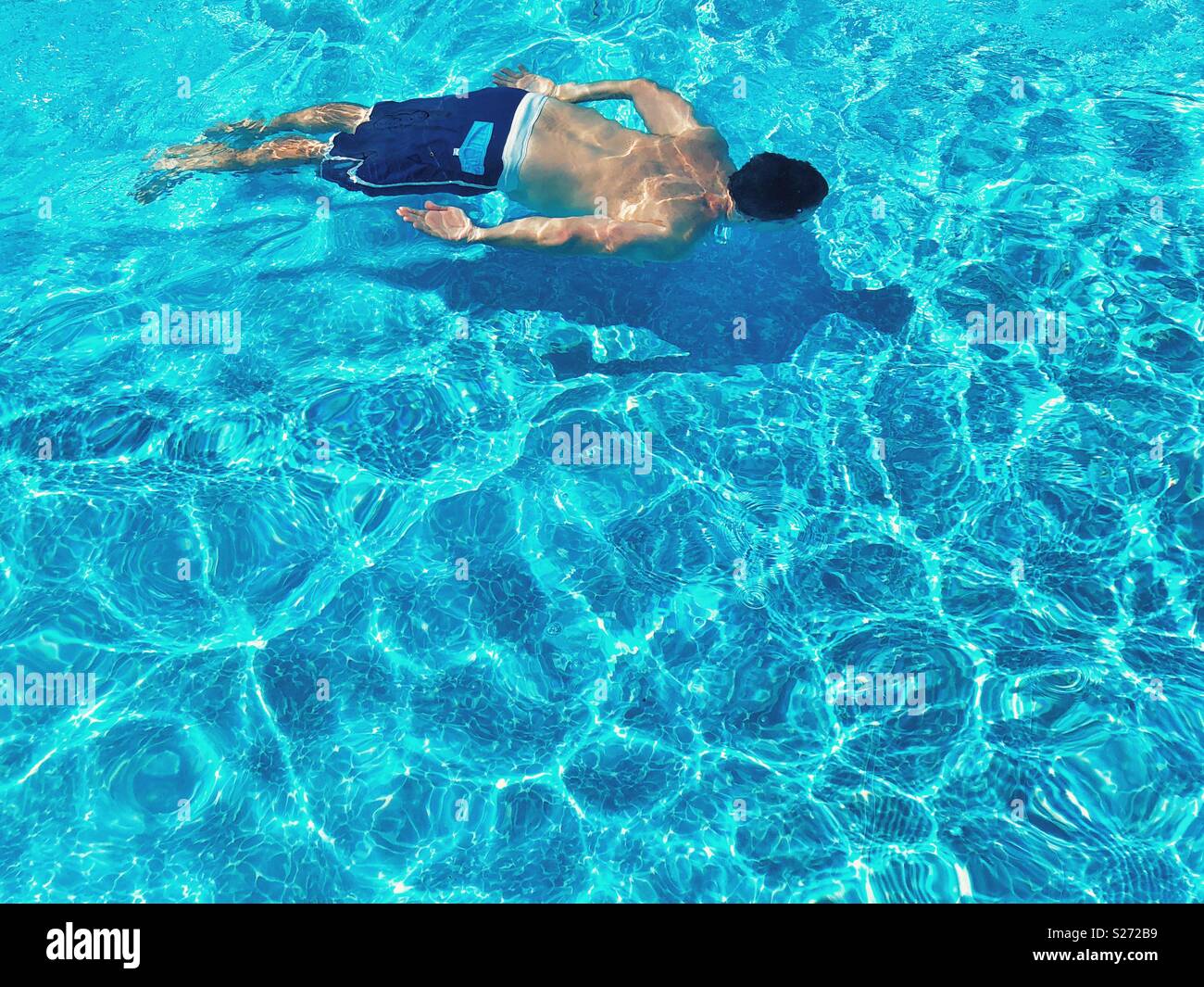 L'homme nage sous l'eau dans une piscine Banque D'Images