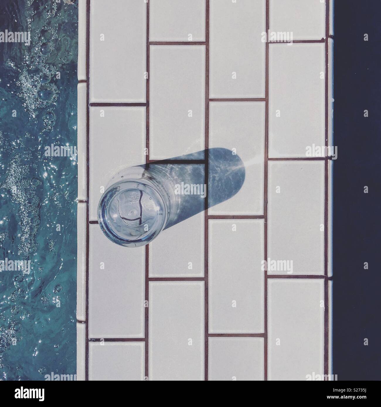 Verre d'eau sur le carrelage de la piscine - Image de stock capturée avec un smartphone