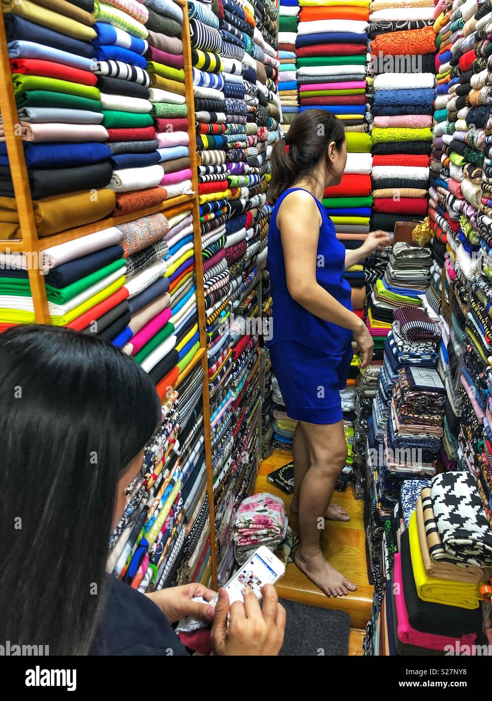 Un distributeur de tissus étroits en décrochage Cho Ben Thanh marché couvert, Ho Chi Minh City, Vietnam. - Image de stock capturée avec un smartphone