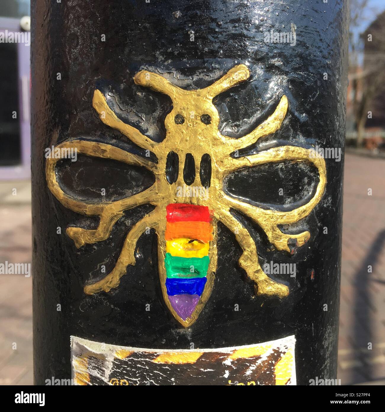 Décoration d'une abeille sur un poteau peint avec un drapeau arc-en-ciel gay Banque D'Images