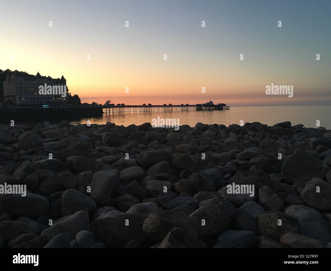 Jetée de Llandudno au coucher du soleil - prises de la plage de galets. Banque D'Images