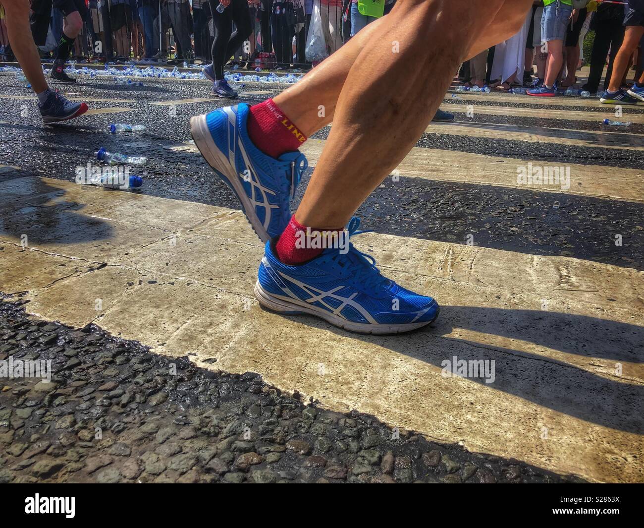 Les coureurs de marathon pieds et des formateurs sur un passage piéton Banque D'Images