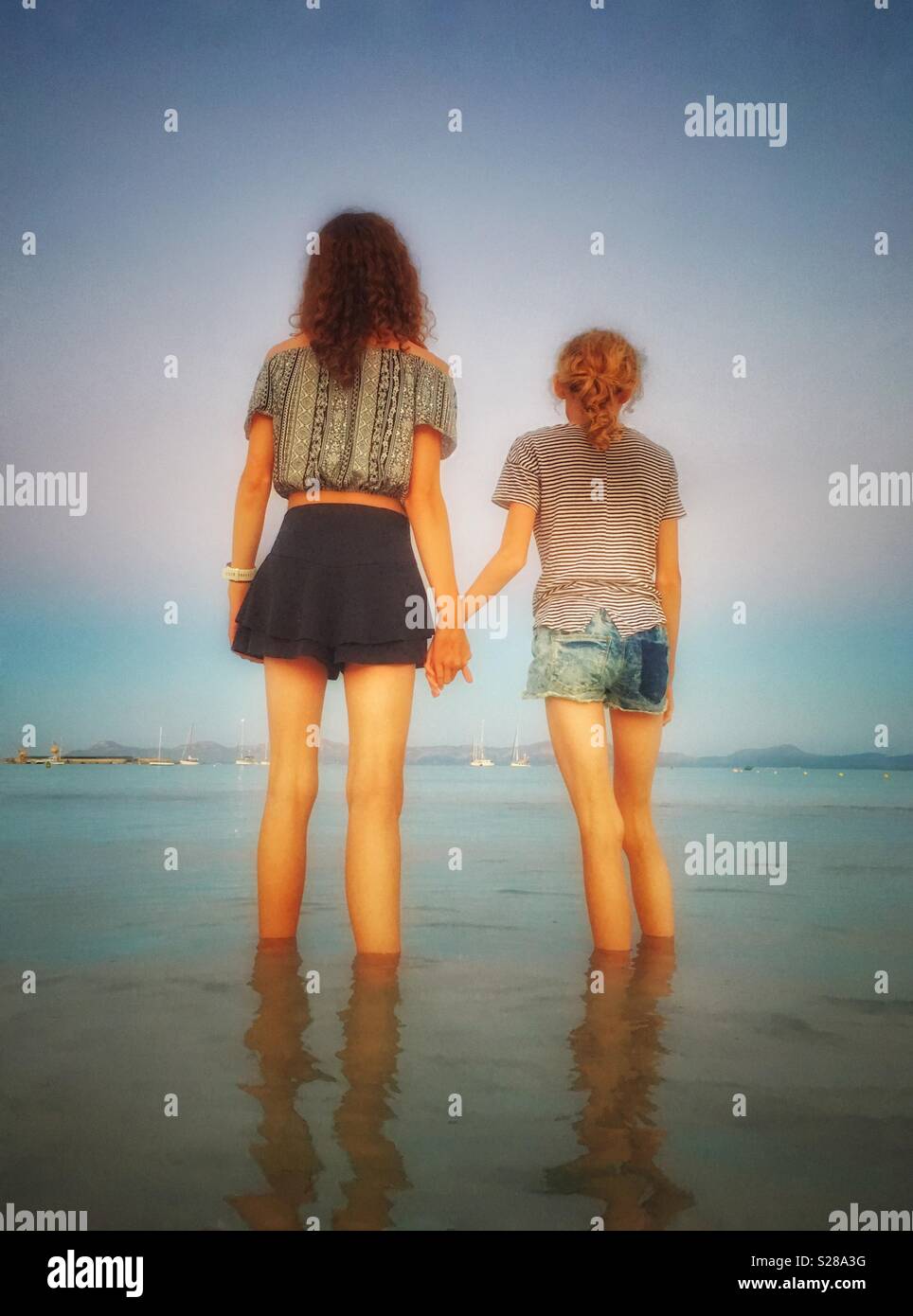 Deux jeunes filles se tenant la main et en pagayant sur la mer Banque D'Images