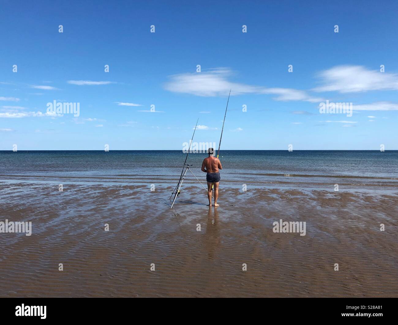 Un homme à la plage de pêche Banque D'Images