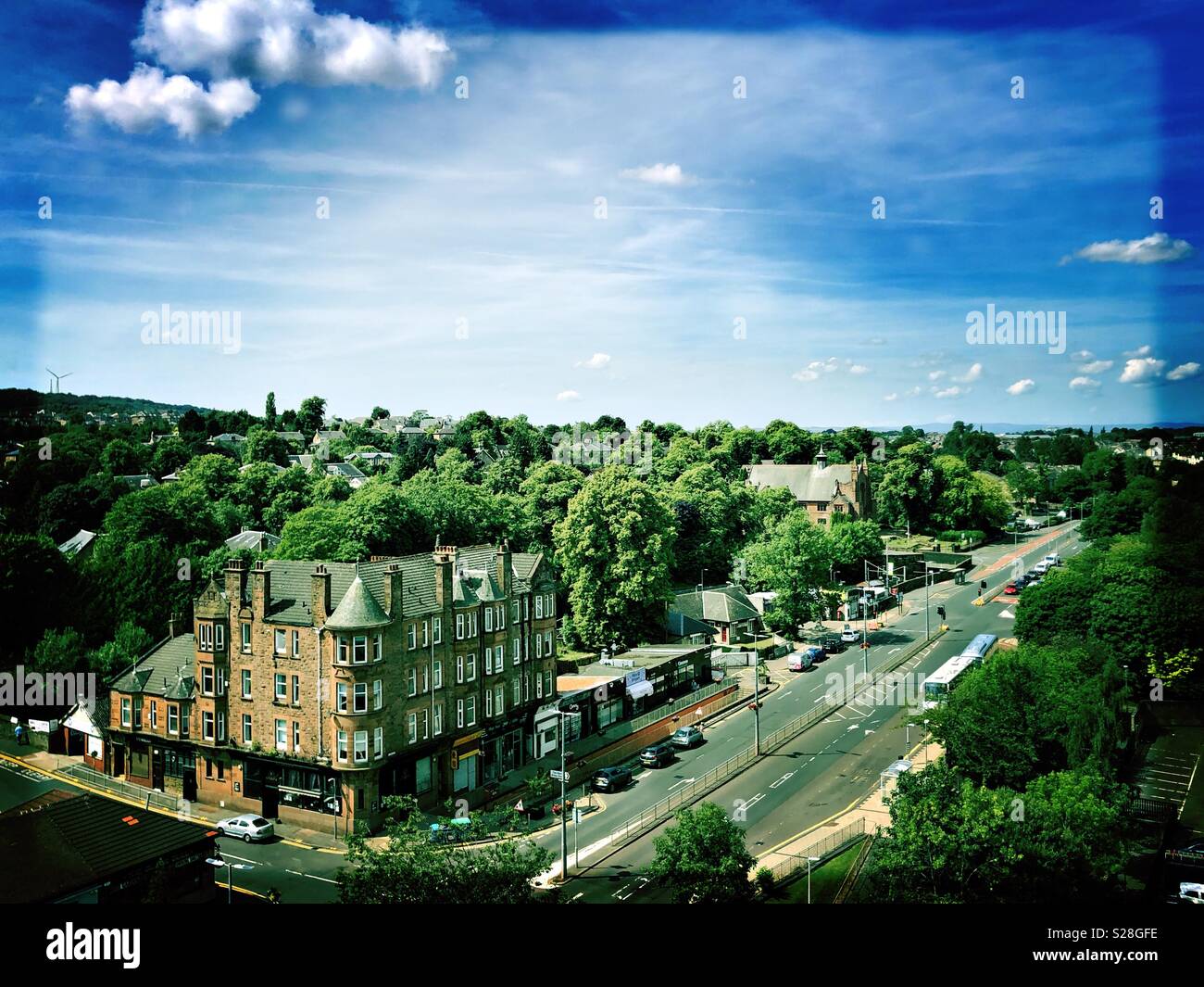 Cambuslang Village en Écosse en juillet, ciel bleu et vert des arbres avec des magasins et des appartements Banque D'Images