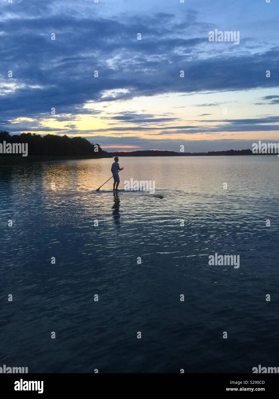 Pagayer sur un lac au coucher du soleil Banque D'Images
