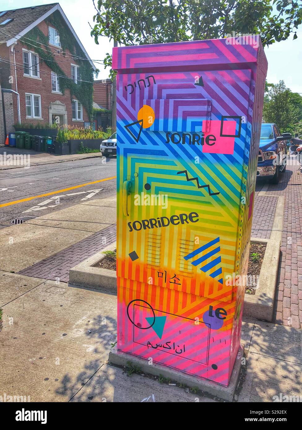 Un utilitaire fort coloré illumine un quartier de la ville avec le mot sourire écrit en différentes langues. - Image de stock capturée avec un smartphone