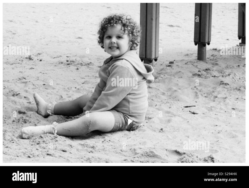 Petite fille assise dans un bac à sable géant Banque D'Images