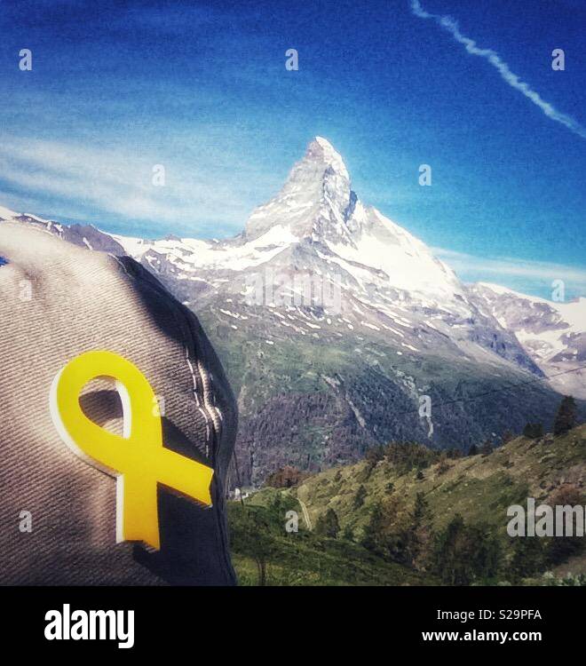 Tourisme catalan avec un ruban jaune coincé dans son cap en face d'une vue sur Matterhorn, Zermatt, Valais ou Valais, Suisse. Symbole de solidarité avec les emprisonnés pro-indépendance des dirigeants catalans. Banque D'Images