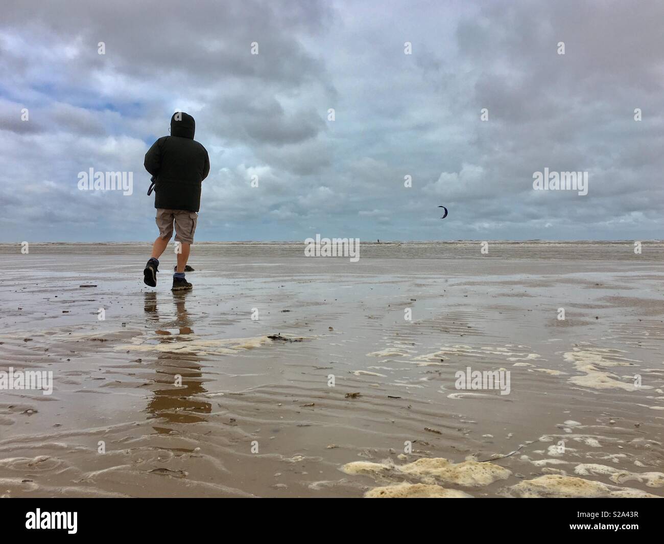 Jour de vent sur la plage, l'homme qui marche Banque D'Images