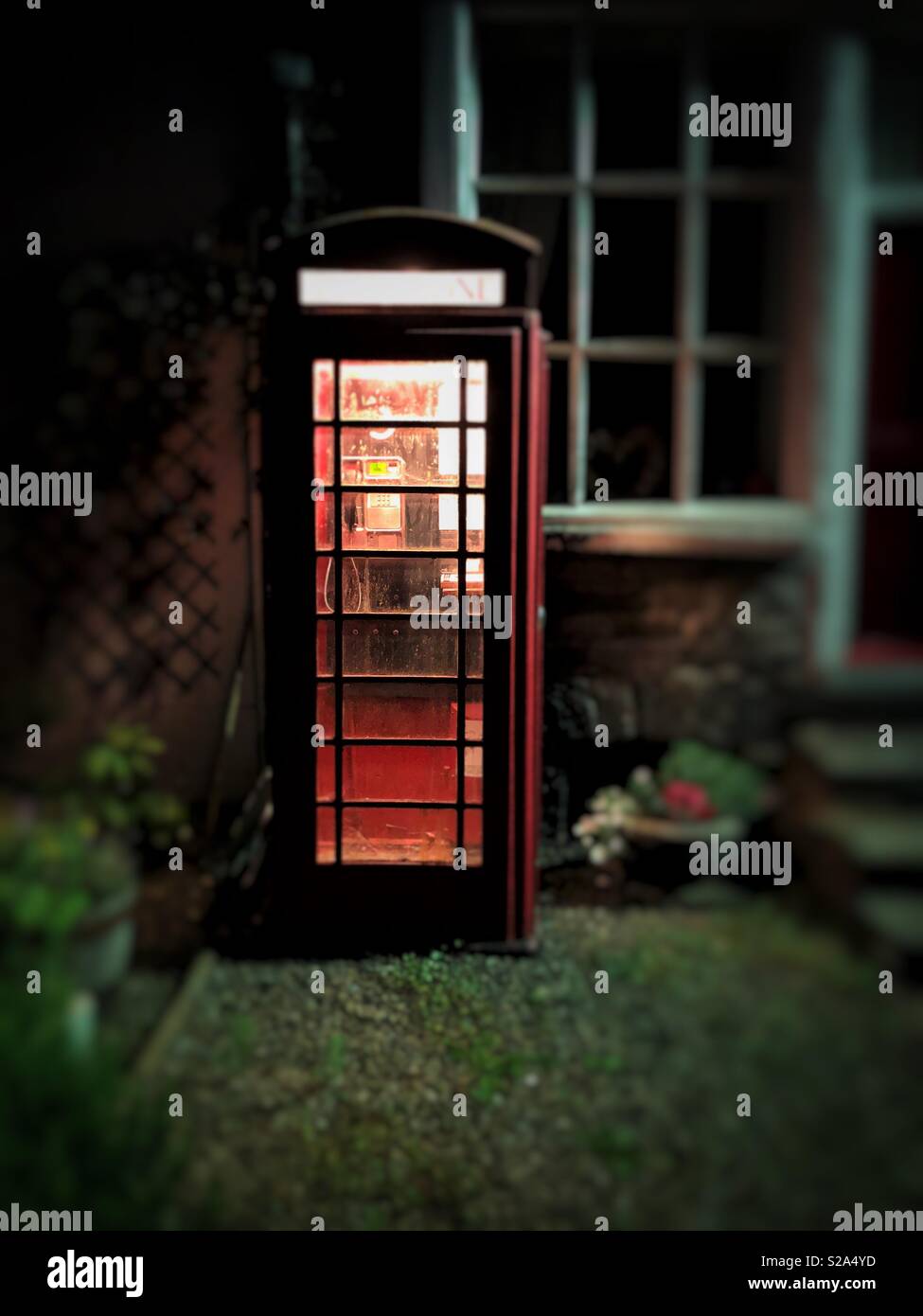 Vieux téléphone rouge fort dans un village gallois à distance. Banque D'Images