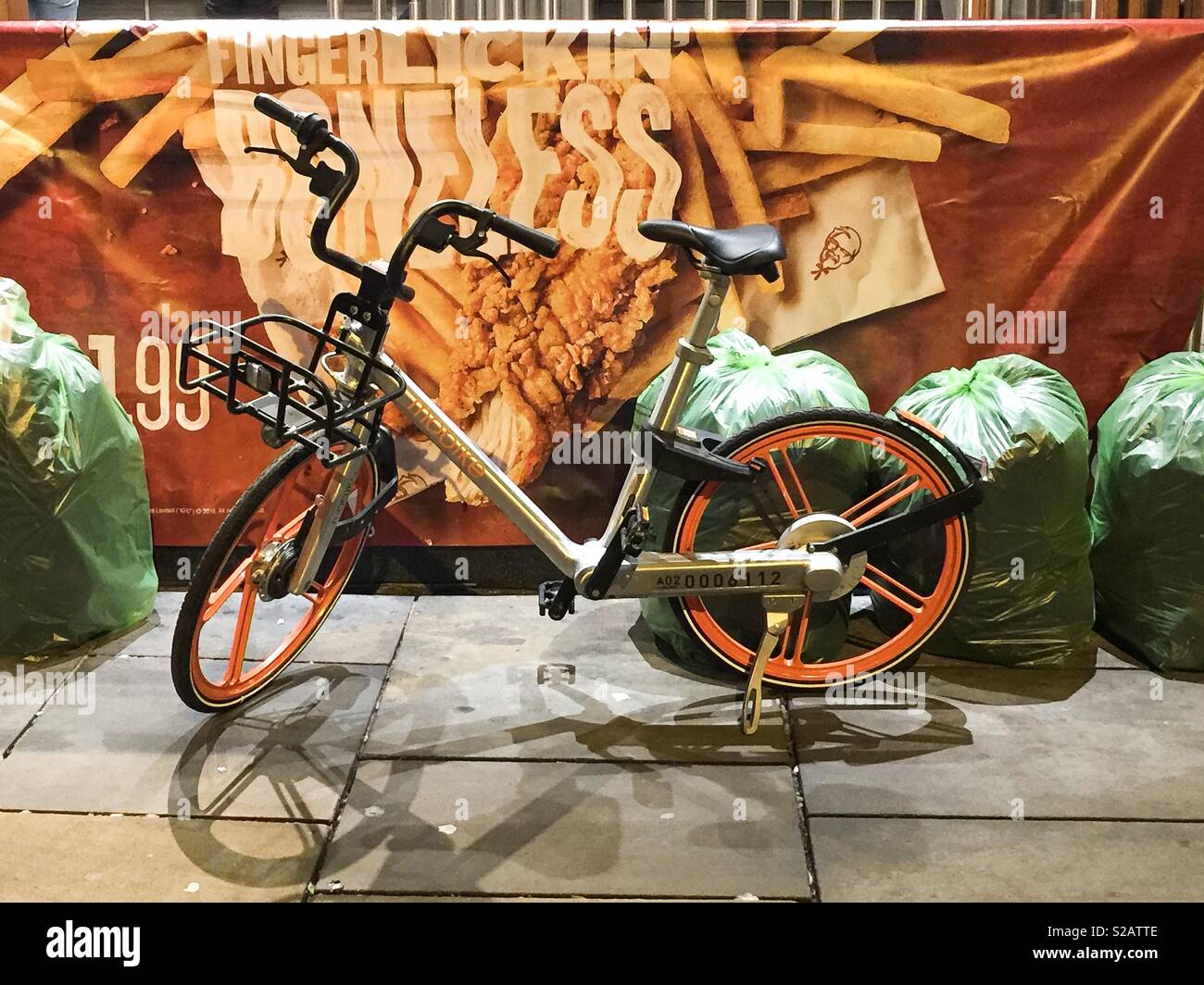 Un Mobike à gauche parmi les sacs poubelle à l'extérieur d'un magasin de restauration rapide à Oxford Banque D'Images