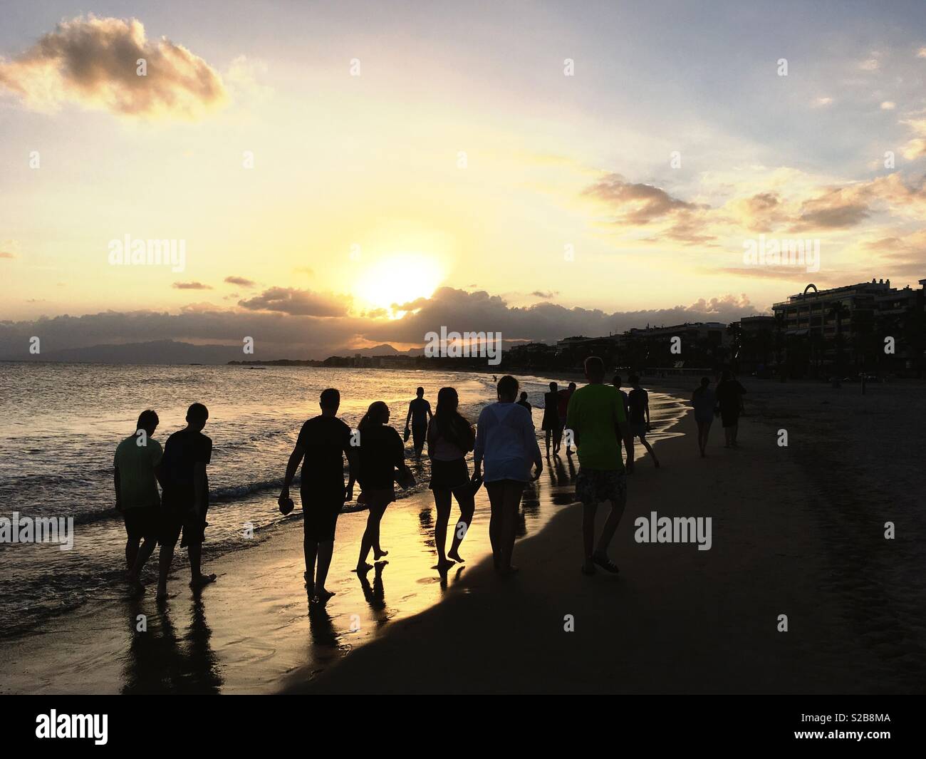 Un groupe d'adolescents en marchant sur une plage au coucher du soleil sur la Costa Dorada à Salou, Catalogne, Espagne Banque D'Images