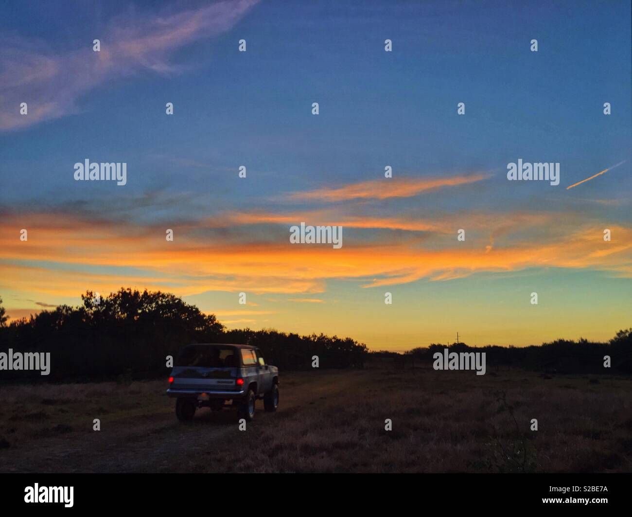 Au volant d'un Chevrolet Blazer vintage dans le coucher du soleil sur une route et des pâturages dans le centre du Texas. Banque D'Images