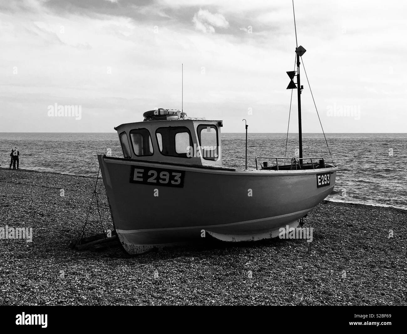 Branscombe beach - bateau de pêche sur les cailloux avec un couple à l'arrière-plan - Noir et blanc - Image de stock capturée avec un smartphone