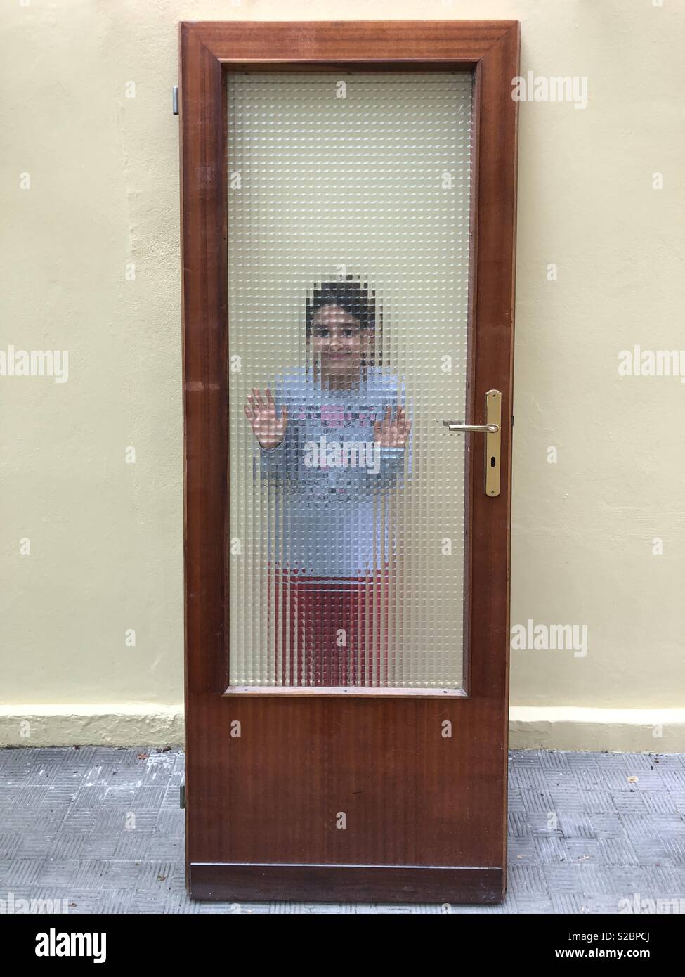 Jeune fille derrière une porte avec verre trempé Banque D'Images