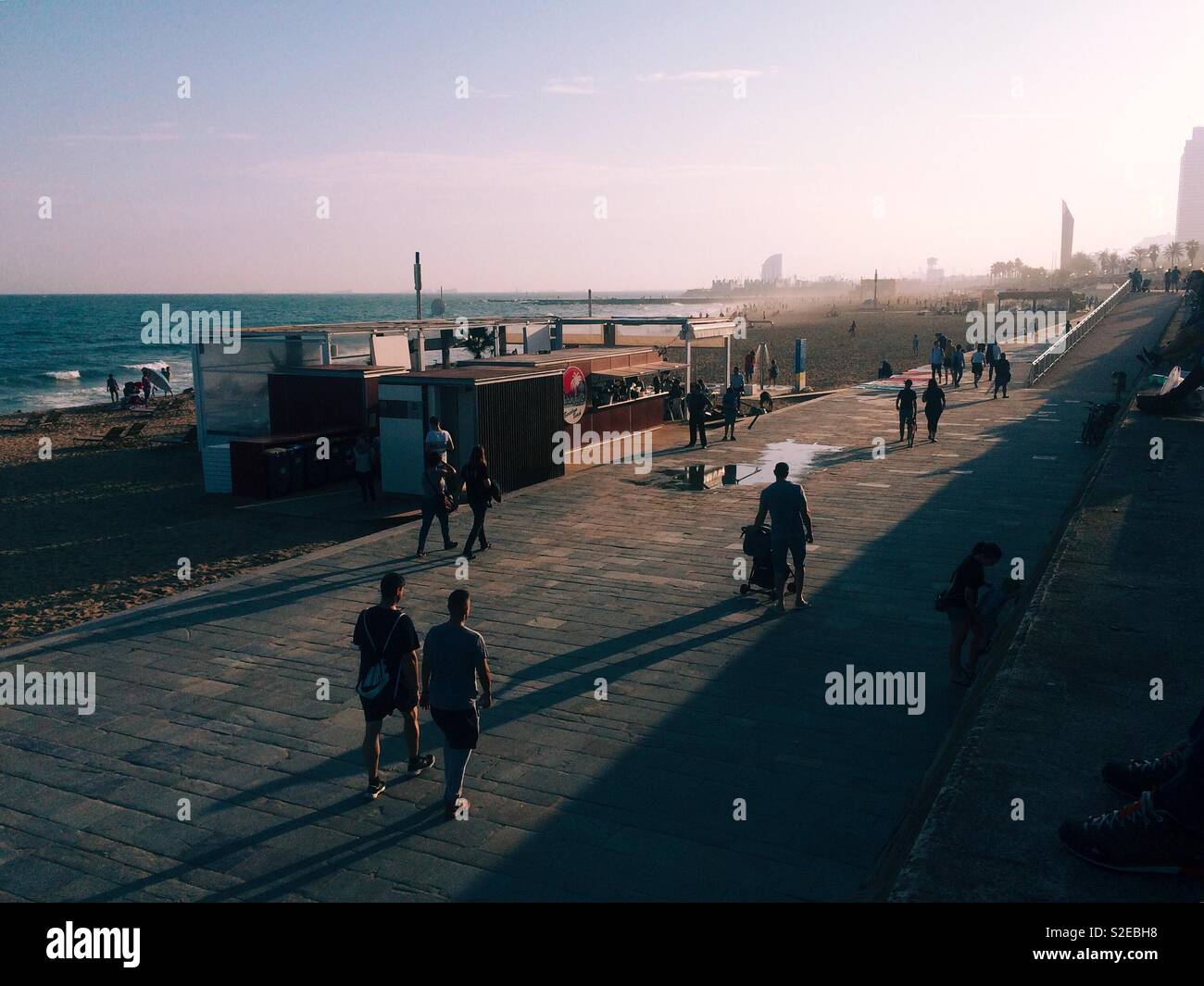 Silhouettes de personnes se promenant le long de la promenade de la plage à El Poblenou plage à Barcelone Espagne profitant du coucher de soleil en automne Banque D'Images