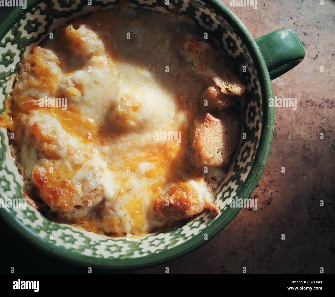 Vue rapprochée de la soupe à l'oignon fait maison recouvert de fromage et de croûtons grillés dans une grande tasse de soupe - Image de stock capturée avec un smartphone