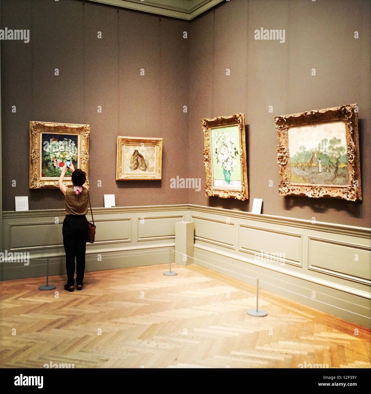 Femme prenant une photo avec son téléphone d'une peinture au Metropolitan Museum of Art, New York. Banque D'Images