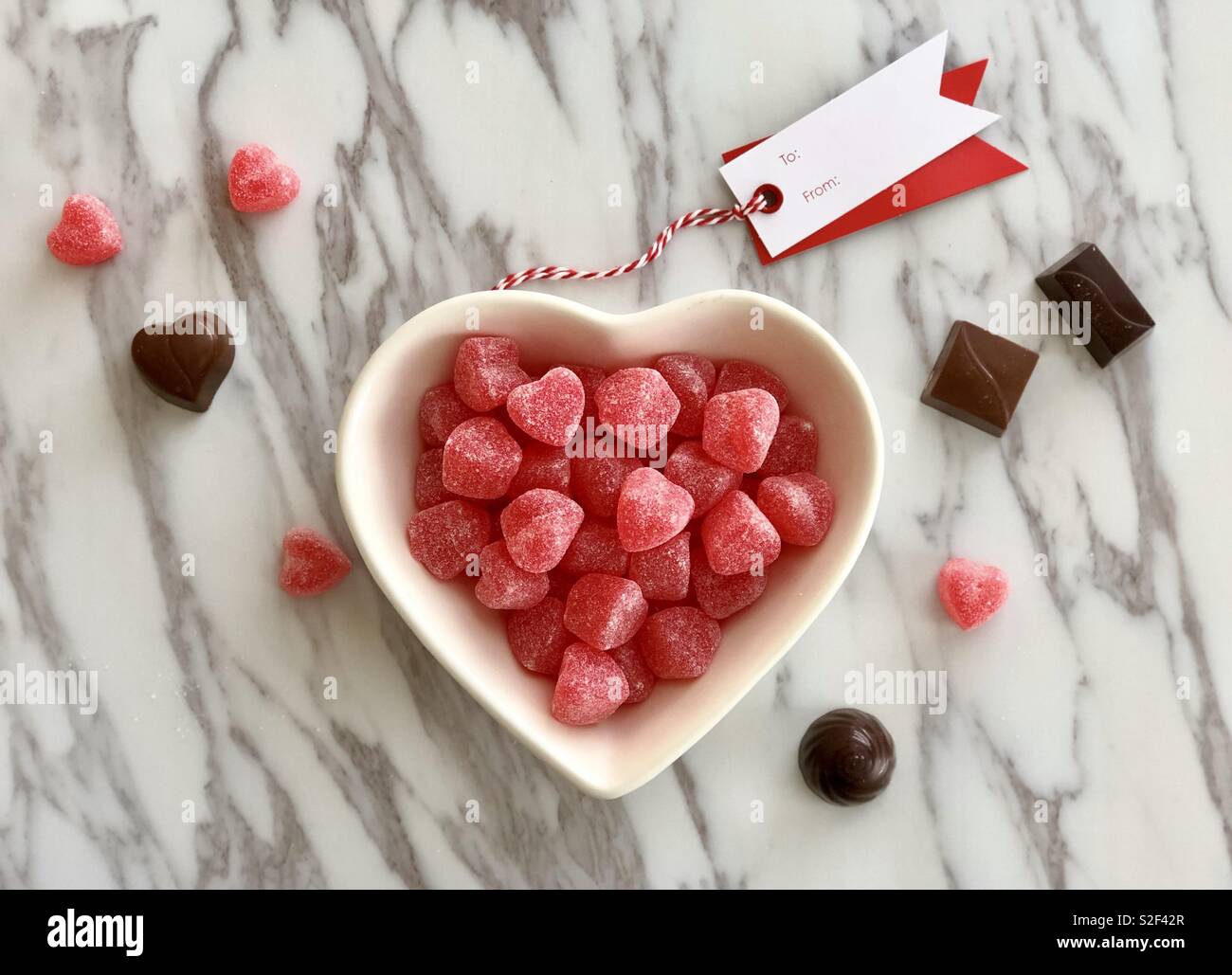 Plat en forme de coeur rouge avec des bonbons et chocolats Banque D'Images