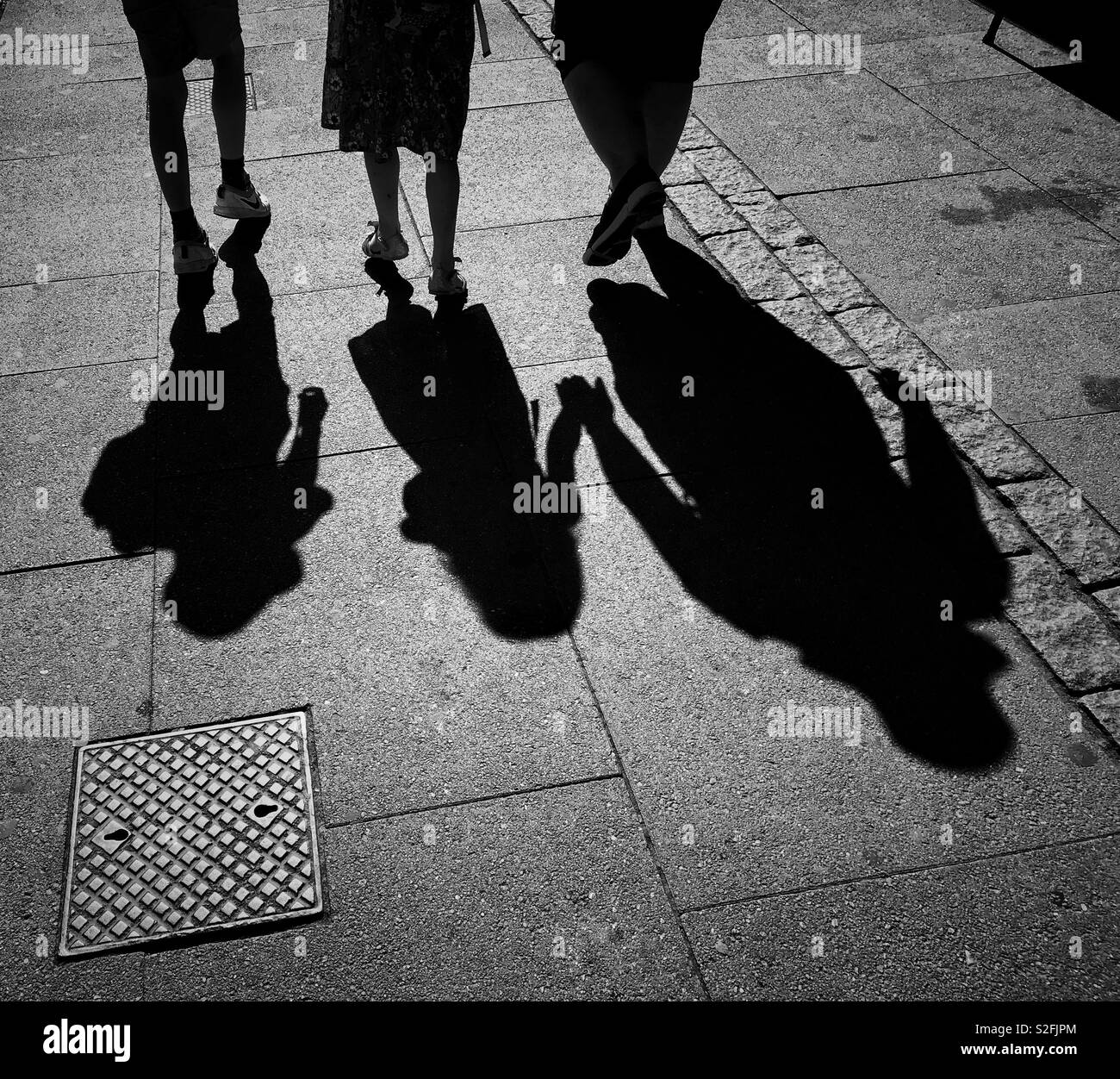 L'ombre de deux enfants pendant qu'elles marchent le long de la chaussée, avec leur mère. C'est une sortie en famille ? Ils ont été enlevés ? Une image avec beaucoup d'utilisations possibles. Photo - © COLIN HOSKINS. Banque D'Images