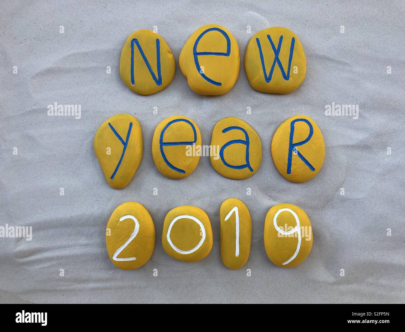 Nouvelle année 2019 avec des pierres peintes en jaune sur du sable blanc Banque D'Images
