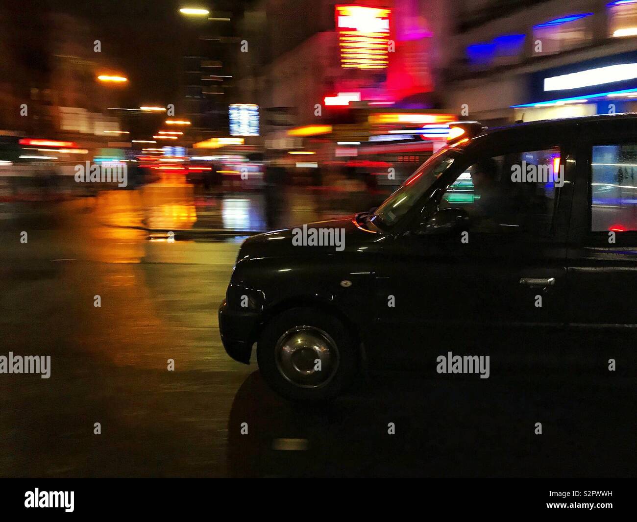 London taxi avec motion blurred les lumières de la ville dans l'arrière-plan Banque D'Images
