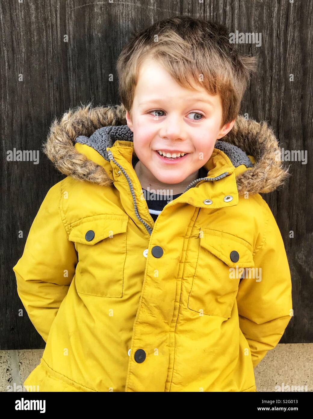Garçon en manteau d'hiver jaune et souriant à côté Photo Stock - Alamy