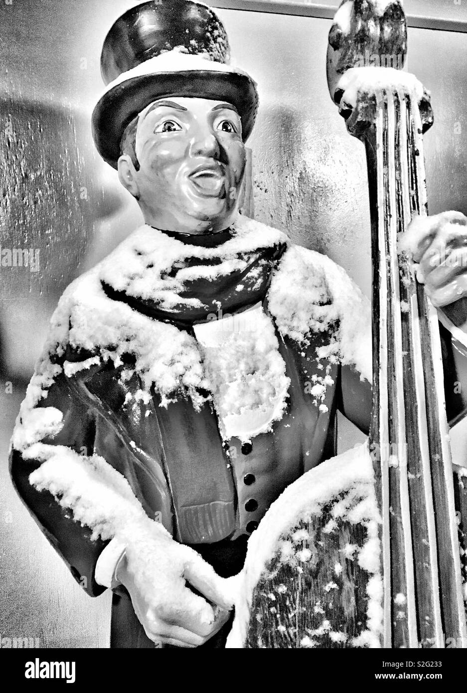 Ornement de Noël avec Violoncelle Chant Caroler manteau écharpe chapeau melon et couvert de neige fraîche en noir et blanc Banque D'Images
