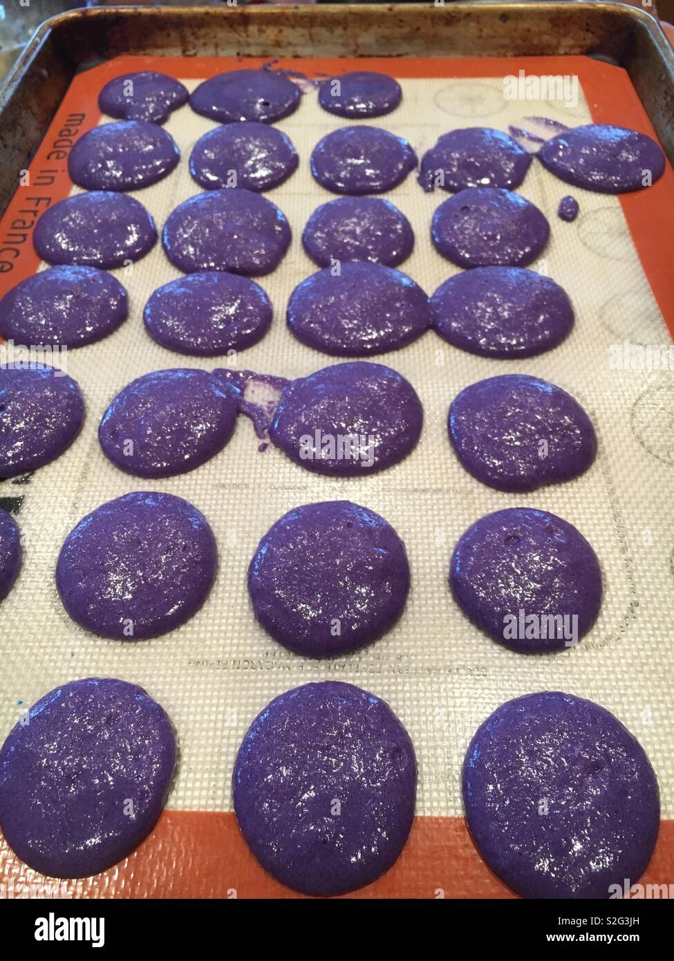 Pâte à biscuits macaron mauve a chuté, même dans des cercles sur un cookie de cuisson. Banque D'Images
