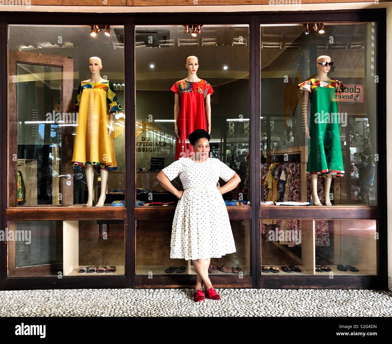 Une femme sudafricaine pose, vêtue d'une robe blanche avec des points et rouge sandales à son